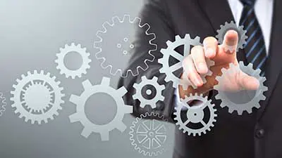 Man in business attire pointing towards the camera, there are gear icons over the image.