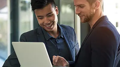 Two men, dressed in business causal, looking at a laptop